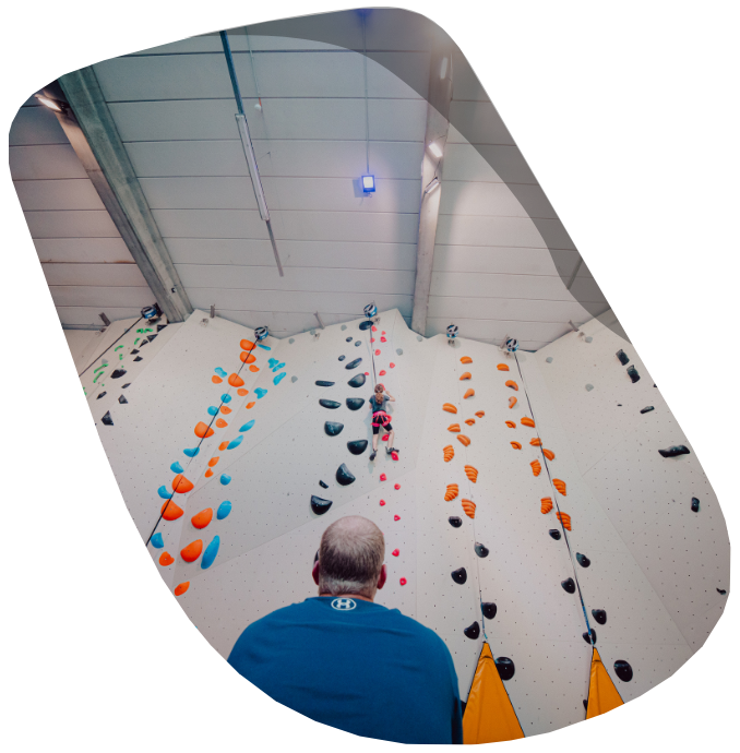 vader kijkt naar dochter aan klimmuur van 8 meter hoog